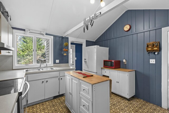 kitchen with sink, white cabinetry, a center island, vaulted ceiling, and white fridge with ice dispenser