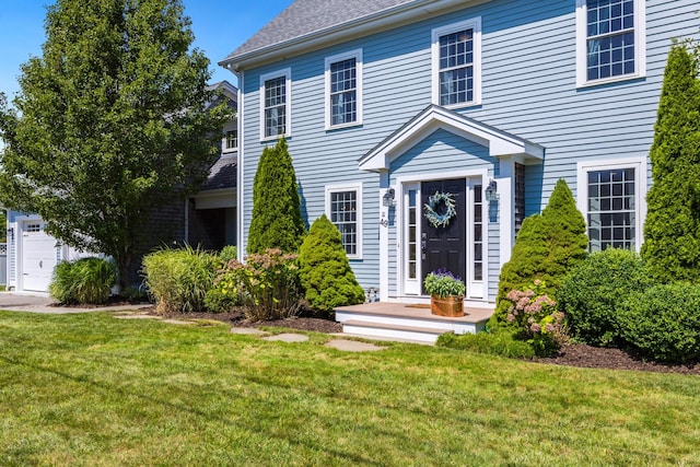 colonial inspired home with a garage and a front lawn