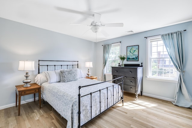 bedroom with multiple windows, ceiling fan, and light hardwood / wood-style floors