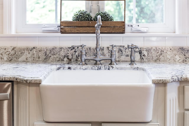 interior details featuring light stone counters, sink, and decorative backsplash