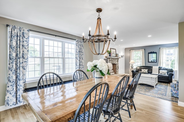 dining room featuring a stone fireplace and light hardwood / wood-style flooring