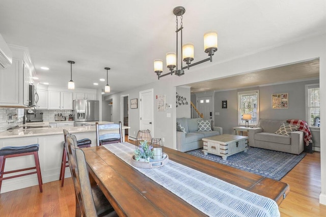 dining room with light wood-style floors, recessed lighting, and a notable chandelier