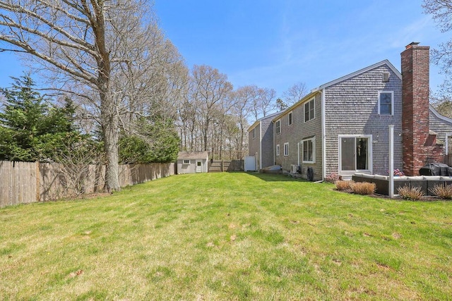 view of yard featuring fence, an outdoor structure, and a storage shed