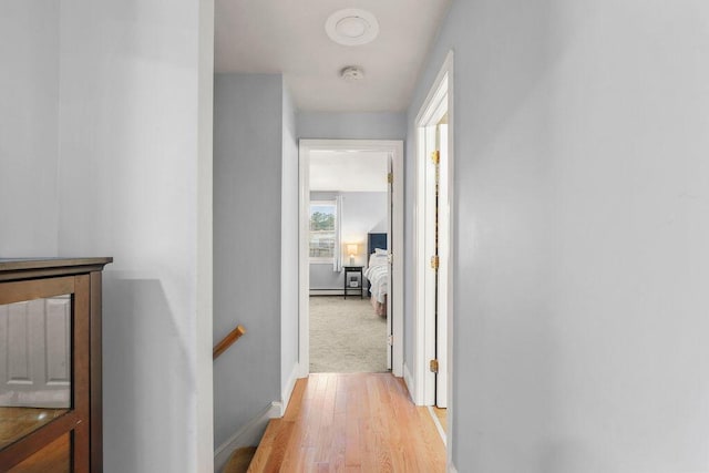 hallway with baseboards, light wood finished floors, and an upstairs landing