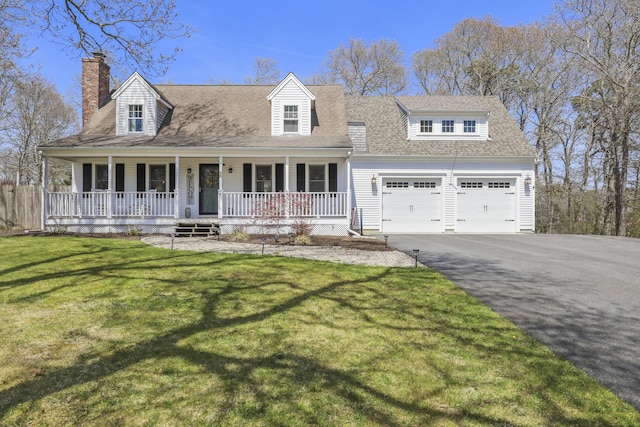 new england style home with a front yard, roof with shingles, a chimney, a porch, and driveway
