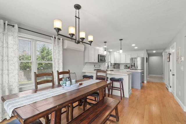 dining space with recessed lighting, baseboards, a wall mounted AC, and light wood finished floors