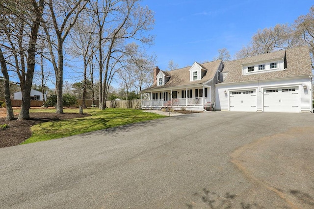 cape cod-style house with covered porch, driveway, a chimney, a front yard, and fence