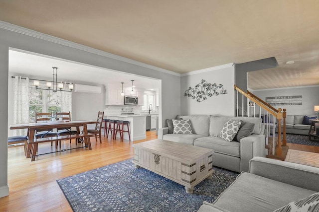 living area featuring crown molding, plenty of natural light, an AC wall unit, and light wood finished floors