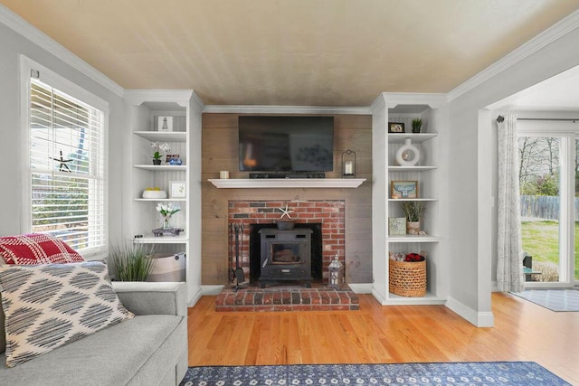 living area with baseboards, a wood stove, built in shelves, and wood finished floors