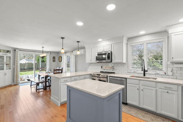 kitchen featuring decorative backsplash, a peninsula, white cabinetry, a sink, and appliances with stainless steel finishes