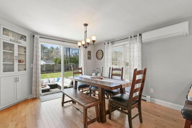 dining room featuring light wood-style floors, a wall unit AC, and a wealth of natural light