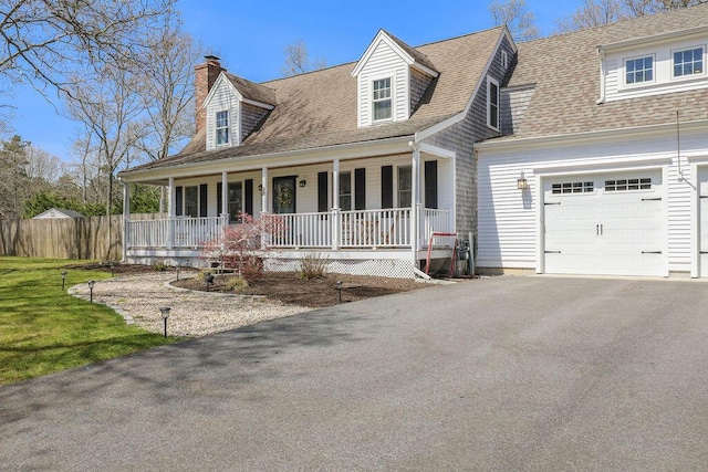 cape cod home with a porch, a chimney, roof with shingles, and aphalt driveway