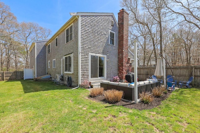 back of house featuring a lawn, a fenced backyard, outdoor lounge area, and a chimney