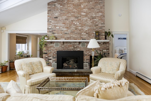 living room featuring wood-type flooring, a brick fireplace, a baseboard heating unit, and high vaulted ceiling