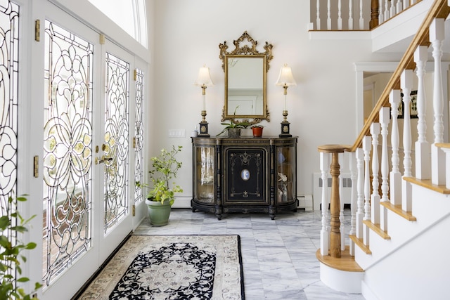 entrance foyer featuring a baseboard heating unit, a towering ceiling, radiator, and french doors