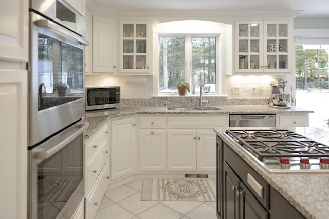 kitchen featuring white cabinetry, sink, light stone countertops, and appliances with stainless steel finishes