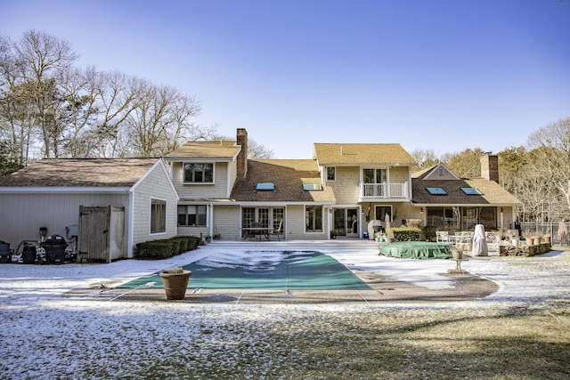 rear view of property featuring a patio, a balcony, and a covered pool