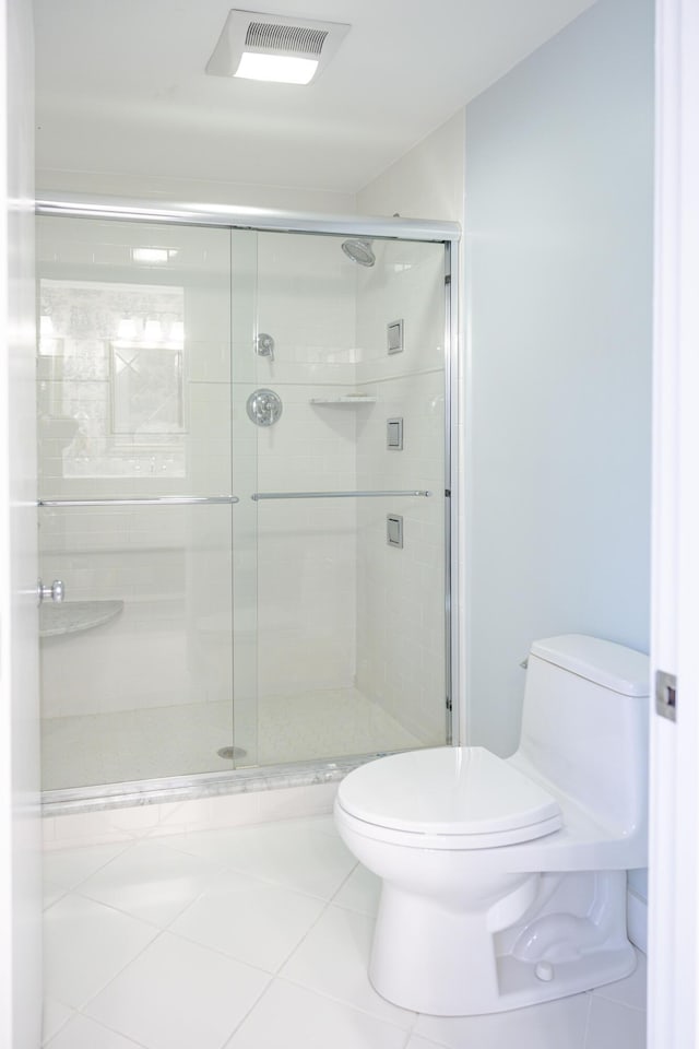 bathroom featuring an enclosed shower, tile patterned floors, and toilet