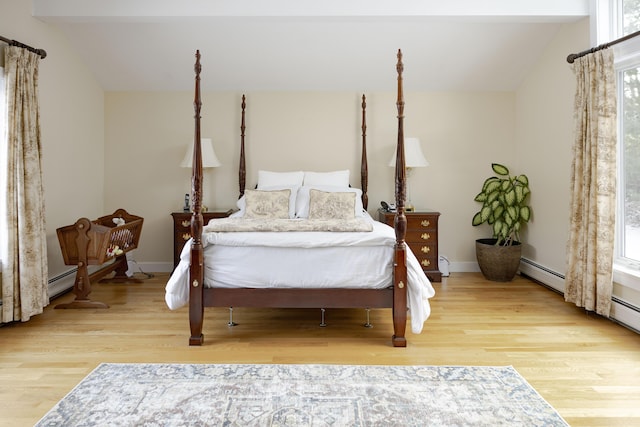 bedroom featuring a baseboard radiator, lofted ceiling, and light hardwood / wood-style flooring