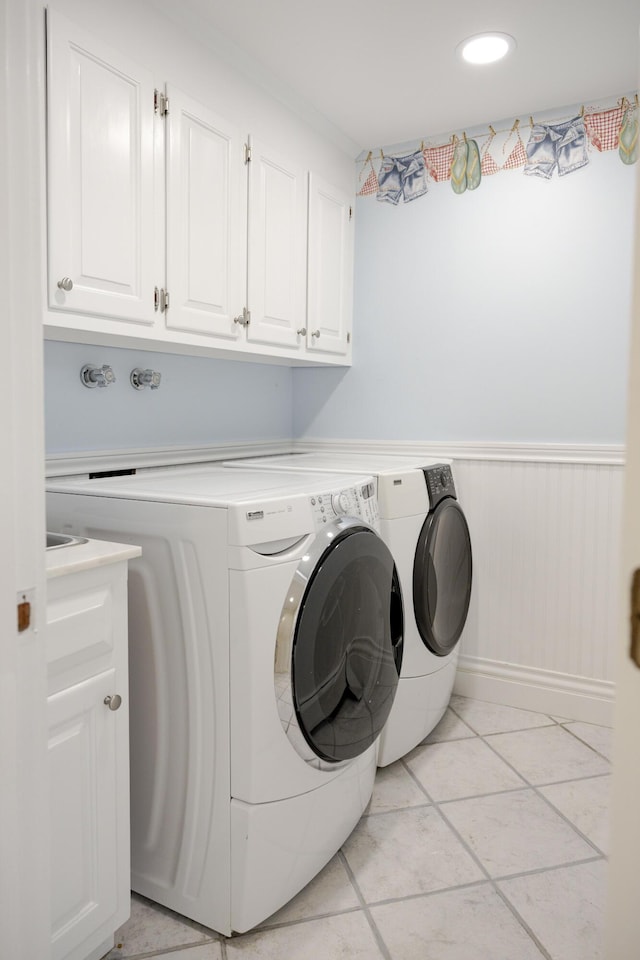 washroom featuring separate washer and dryer, cabinets, and light tile patterned flooring