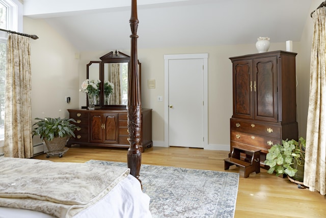 bedroom featuring a baseboard radiator, lofted ceiling, light hardwood / wood-style floors, and multiple windows