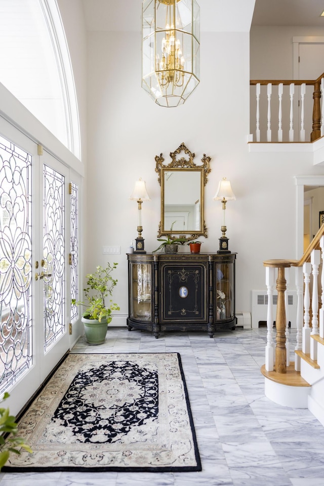 foyer entrance with a notable chandelier, french doors, and a high ceiling