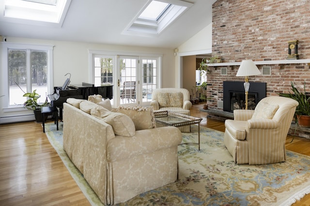 living room featuring a brick fireplace, vaulted ceiling with skylight, and light hardwood / wood-style floors