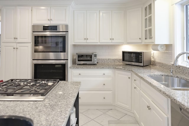 kitchen featuring sink, stainless steel appliances, white cabinets, and light stone countertops