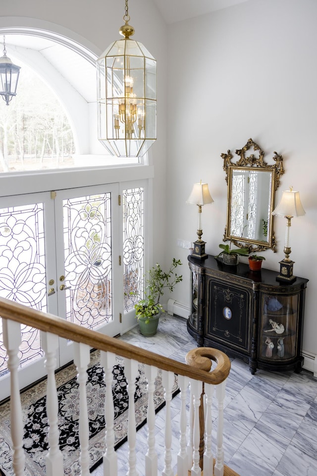 entryway with a high ceiling, a baseboard heating unit, a chandelier, and french doors