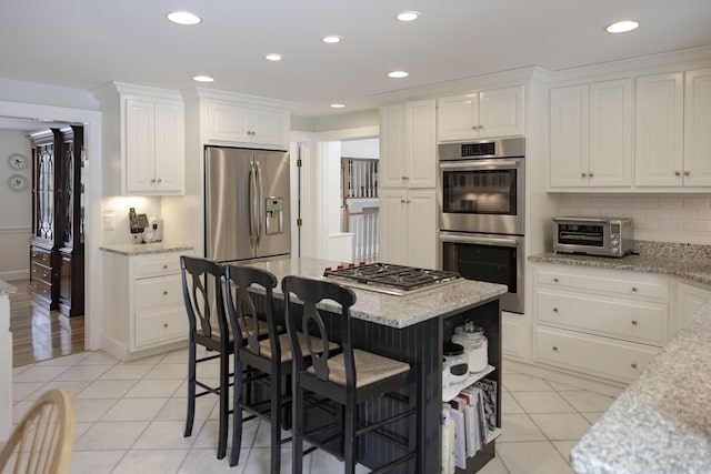 98 Bunker Hill Rd, Osterville, MA 02655 - kitchen with stainless steel appliances, white cabinets, light tile patterned floors, a breakfast bar, and recessed lighting
