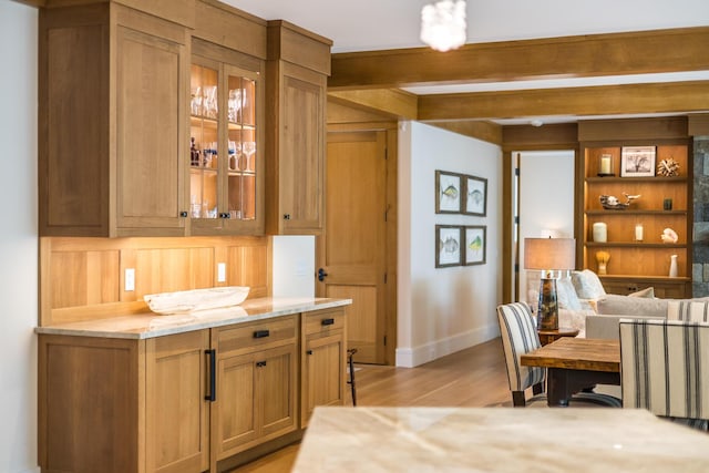 2 Bridge St, East Falmouth, MA 02536 - kitchen featuring baseboards, light wood-type flooring, glass insert cabinets, light stone counters, and beam ceiling