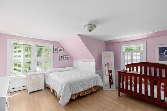 bedroom with a baseboard radiator, lofted ceiling, and light hardwood / wood-style flooring