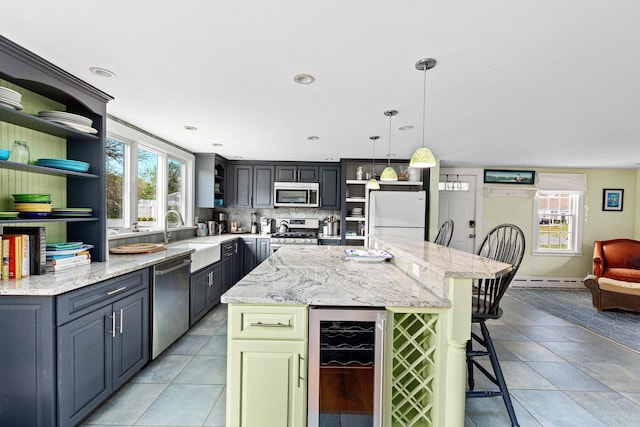 kitchen with sink, appliances with stainless steel finishes, wine cooler, a kitchen island, and decorative light fixtures