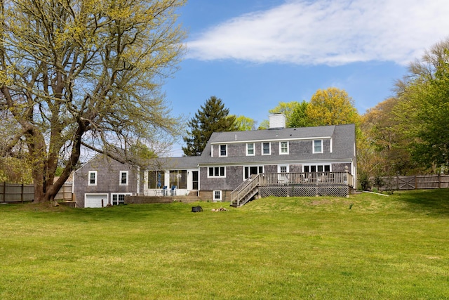 rear view of house with a garage, a deck, and a lawn