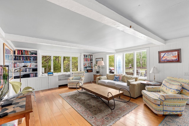 living room featuring beamed ceiling, radiator heating unit, built in shelves, and light hardwood / wood-style floors