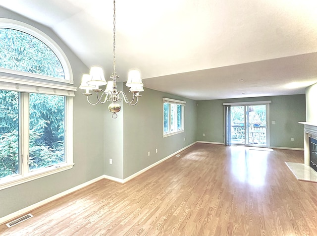 unfurnished dining area featuring wood finished floors, a notable chandelier, lofted ceiling, and visible vents