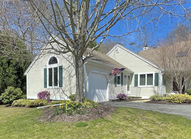 view of front facade with a garage, a front lawn, and aphalt driveway