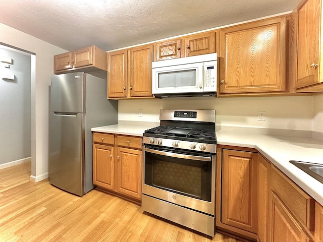 kitchen featuring stainless steel appliances, light hardwood / wood-style floors, and a textured ceiling