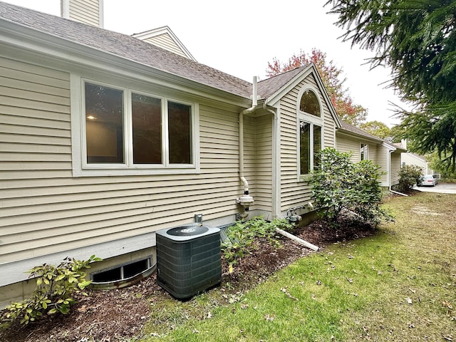 view of side of home with central AC unit and a yard