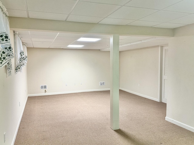 finished basement featuring baseboards, visible vents, a drop ceiling, and carpet