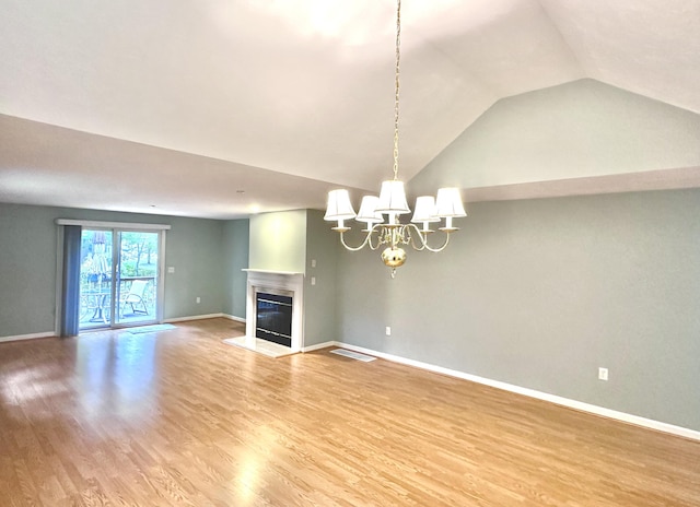 unfurnished living room featuring an inviting chandelier, a glass covered fireplace, light wood-style flooring, baseboards, and vaulted ceiling