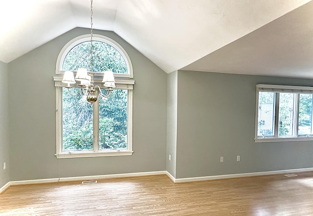 interior space featuring a healthy amount of sunlight, wood finished floors, and a notable chandelier