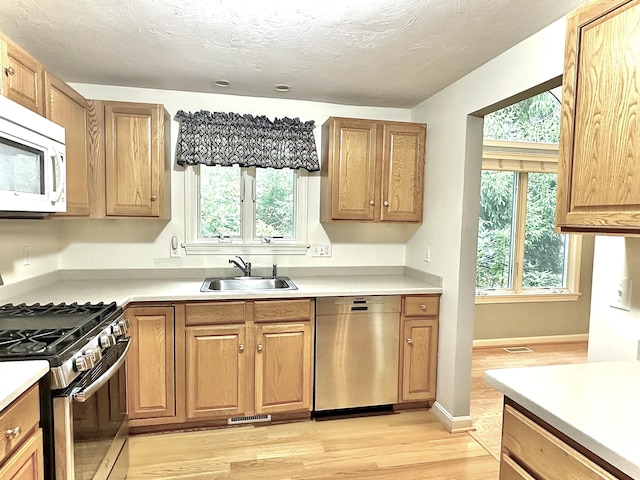 kitchen featuring a sink, light countertops, stainless steel appliances, light wood-type flooring, and visible vents