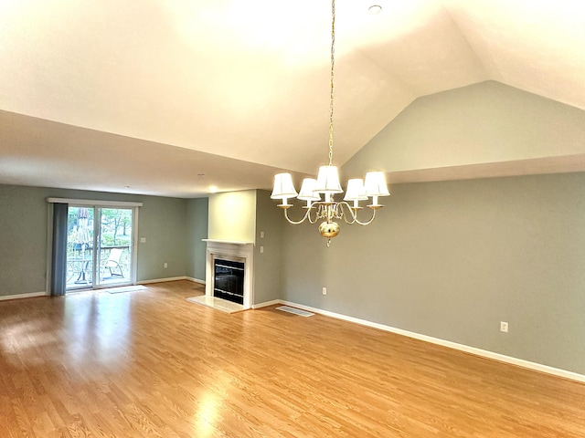 unfurnished living room with hardwood / wood-style flooring, lofted ceiling, and a notable chandelier