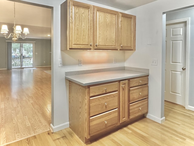 kitchen with baseboards, light wood finished floors, and a notable chandelier