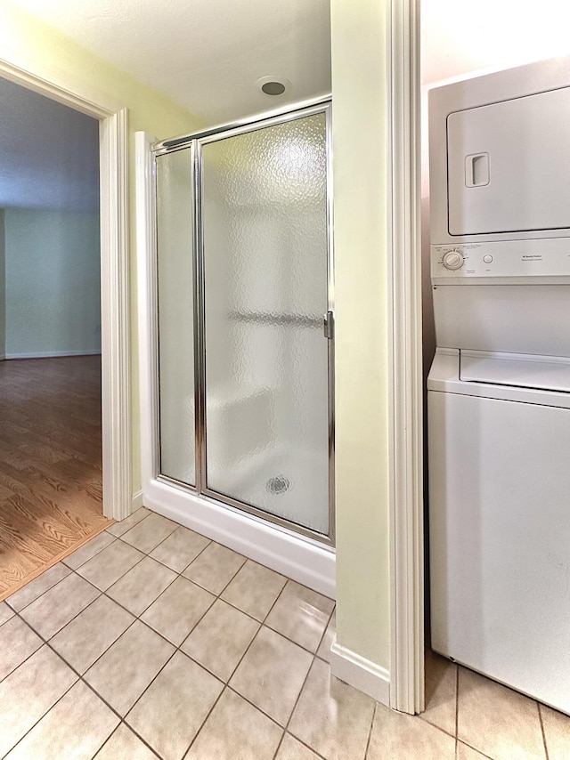 bathroom featuring walk in shower, stacked washer and clothes dryer, and tile patterned floors