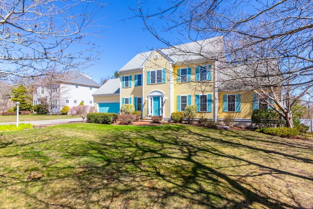 colonial-style house with a front yard, an attached garage, and driveway