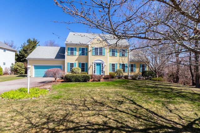 colonial-style house with a garage, driveway, and a front lawn