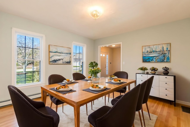 dining space featuring baseboard heating, a healthy amount of sunlight, light wood finished floors, and baseboards