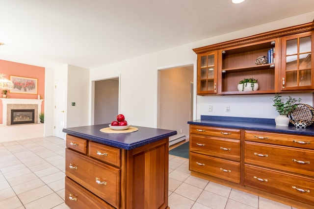 kitchen featuring light tile patterned floors, glass insert cabinets, a baseboard heating unit, and dark countertops